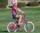 Fille à bicyclette dans le parc au printemps